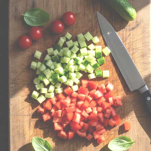 нарезанные помидоры и огурцы на разделочной доске
